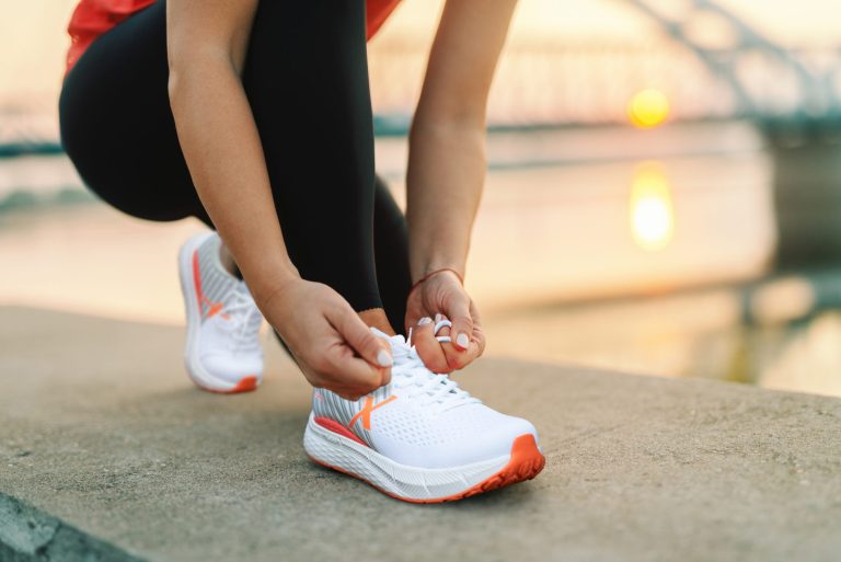 Picture of a woman kneeling down and tying her shoes.