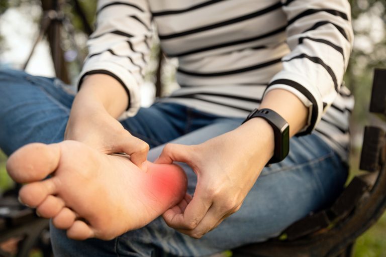Plantar fasciitis,asian young woman holding her feet and massage with her hand suffer from tendon